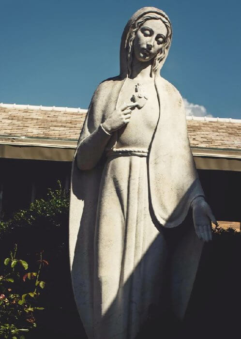 A statue of Mother Mary in a garden.